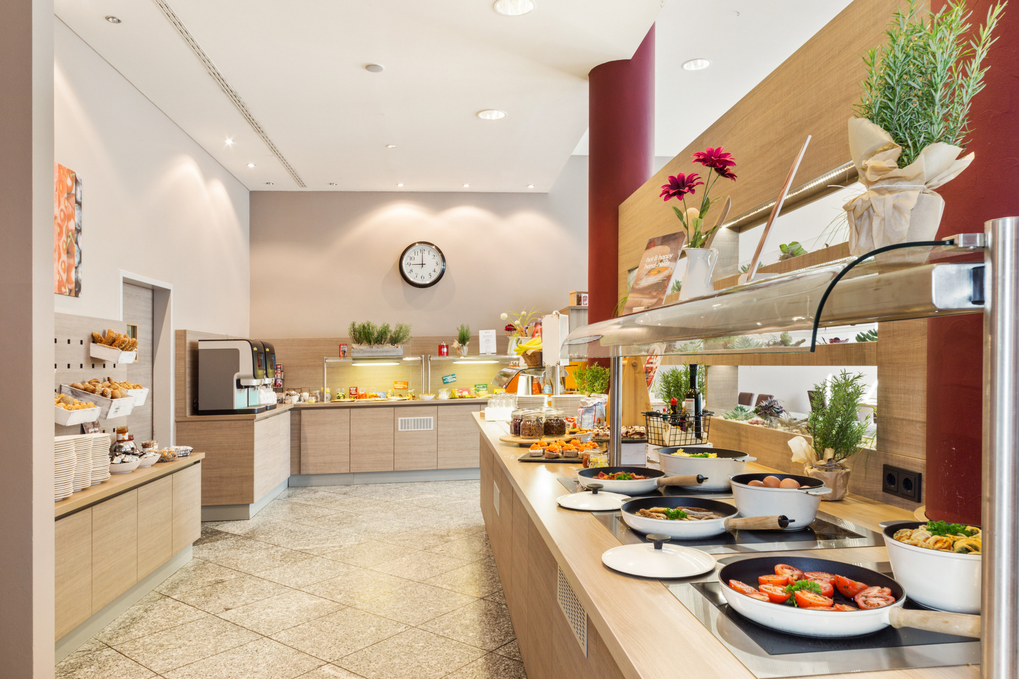 Frühstücksbuffet mit verschiedenen warmen Speisen in Pfannen