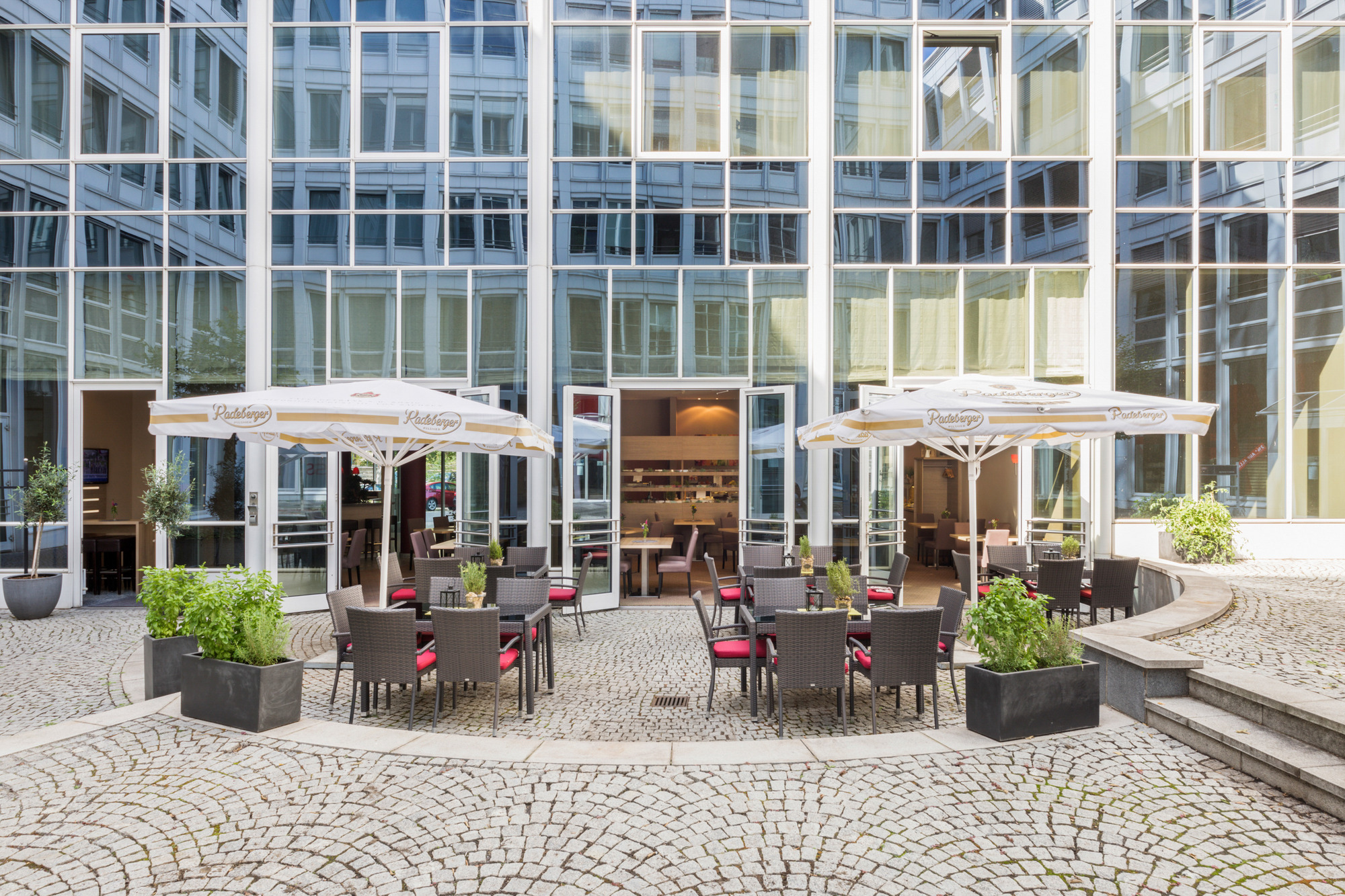 Terrasse im Sonnenlicht mit Sonnenschirmen und Tischgruppen